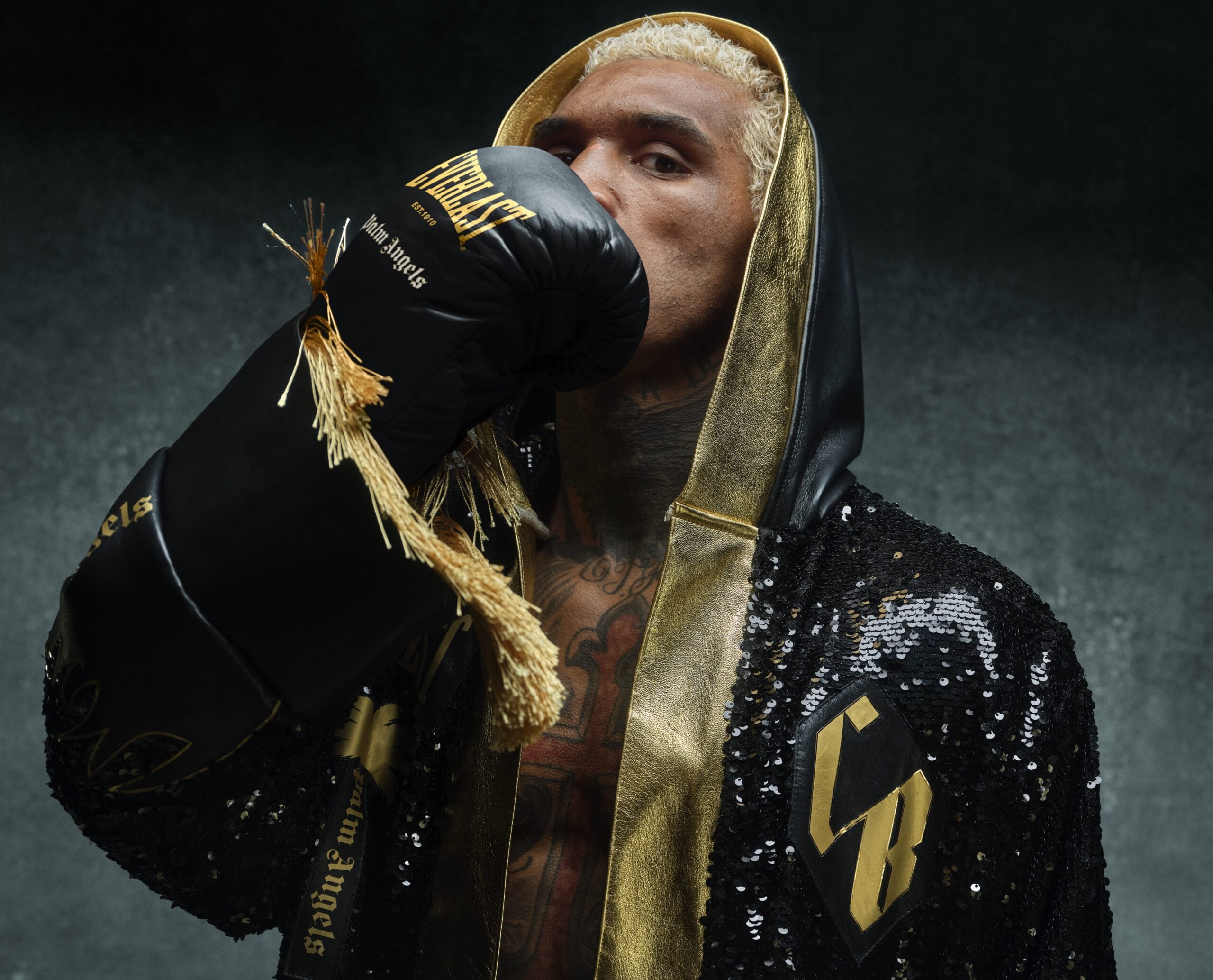 Conor Benn in a hooded robe holding an Everlast x Palm Angels glove to his face