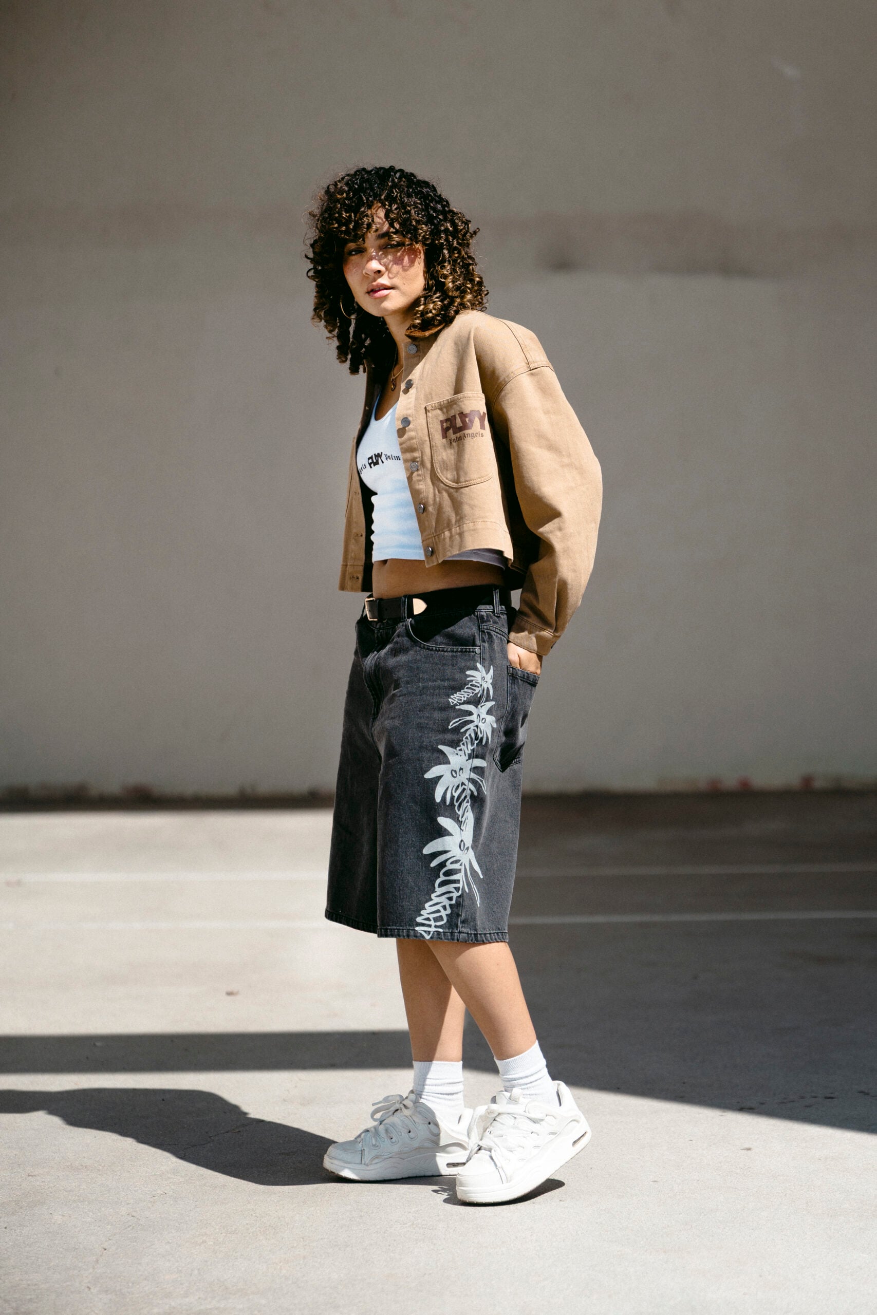 Woman in a tan jacket and printed denim shorts