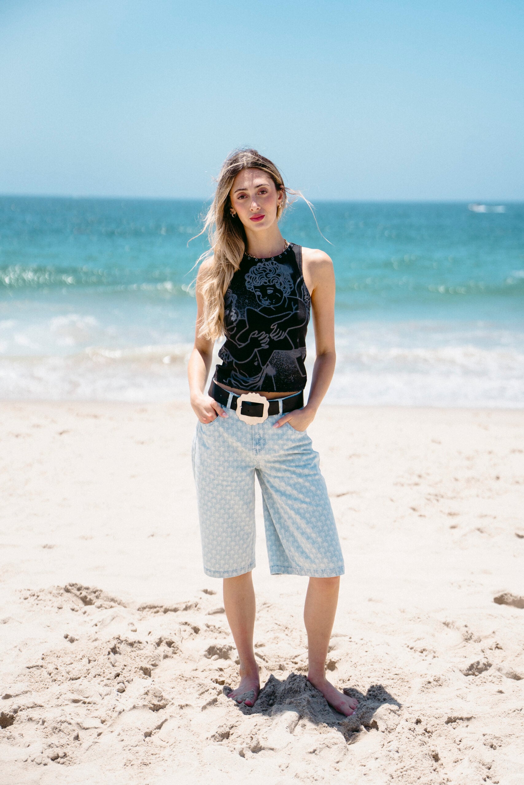 Woman in a black tank top and blue shorts on a beach