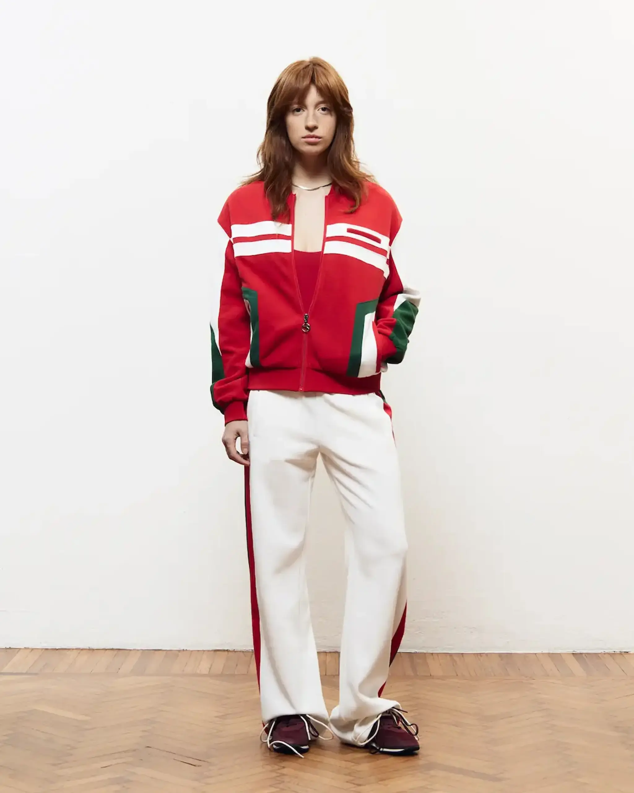 Model in a red track jacket and white striped trousers