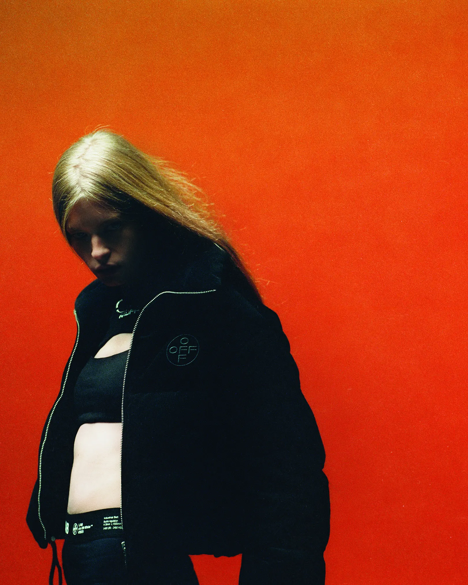 Model in a black Off-White cropped puffer jacket against orange