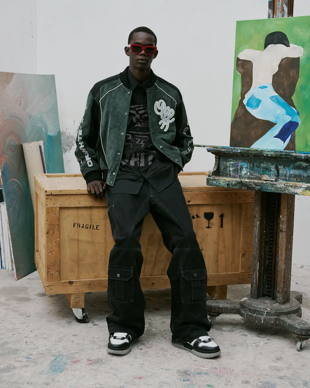 Man in a green Off-White varsity jacket and cargo trousers in a studio