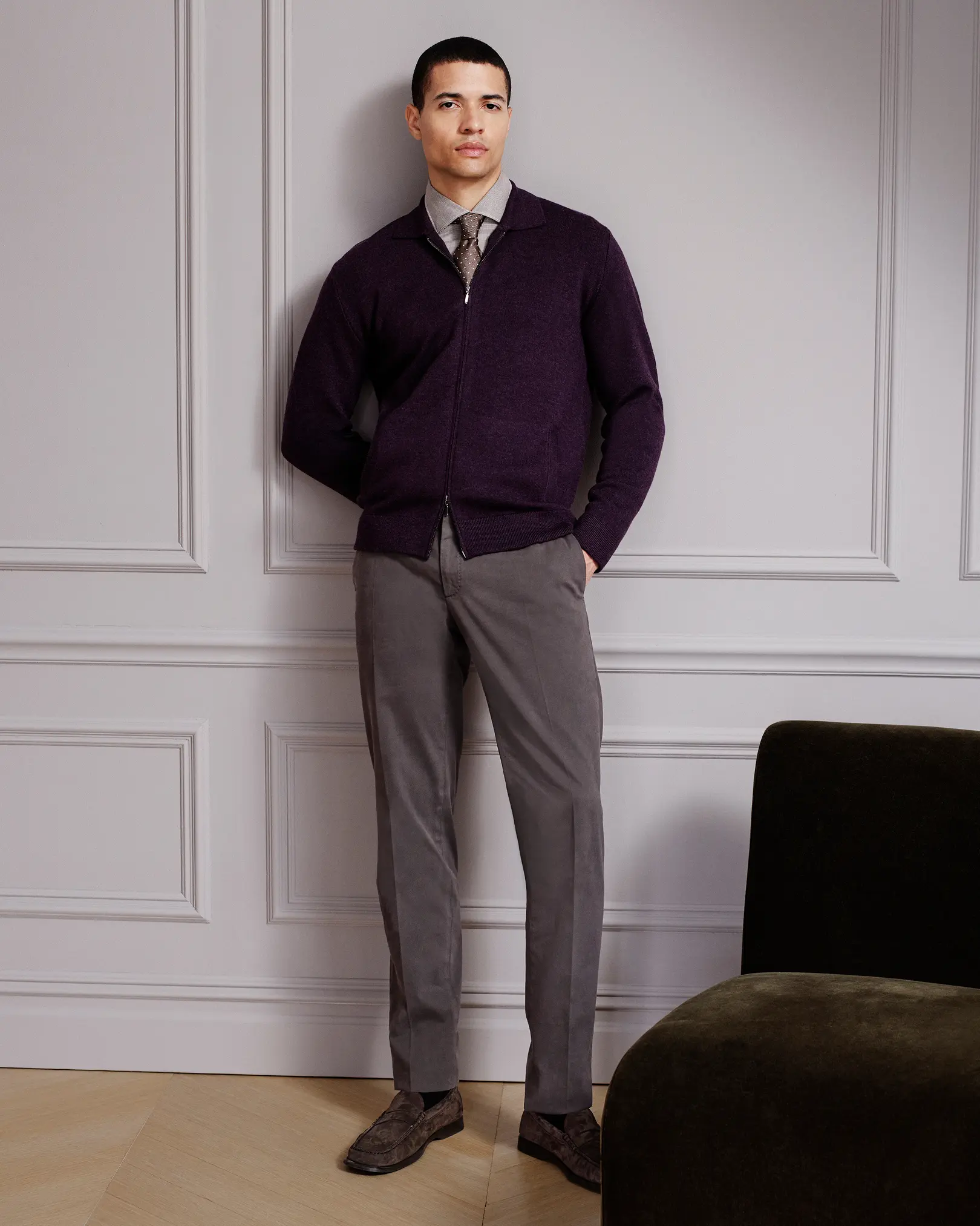 Man in a purple zip cardigan, tie and grey trousers
