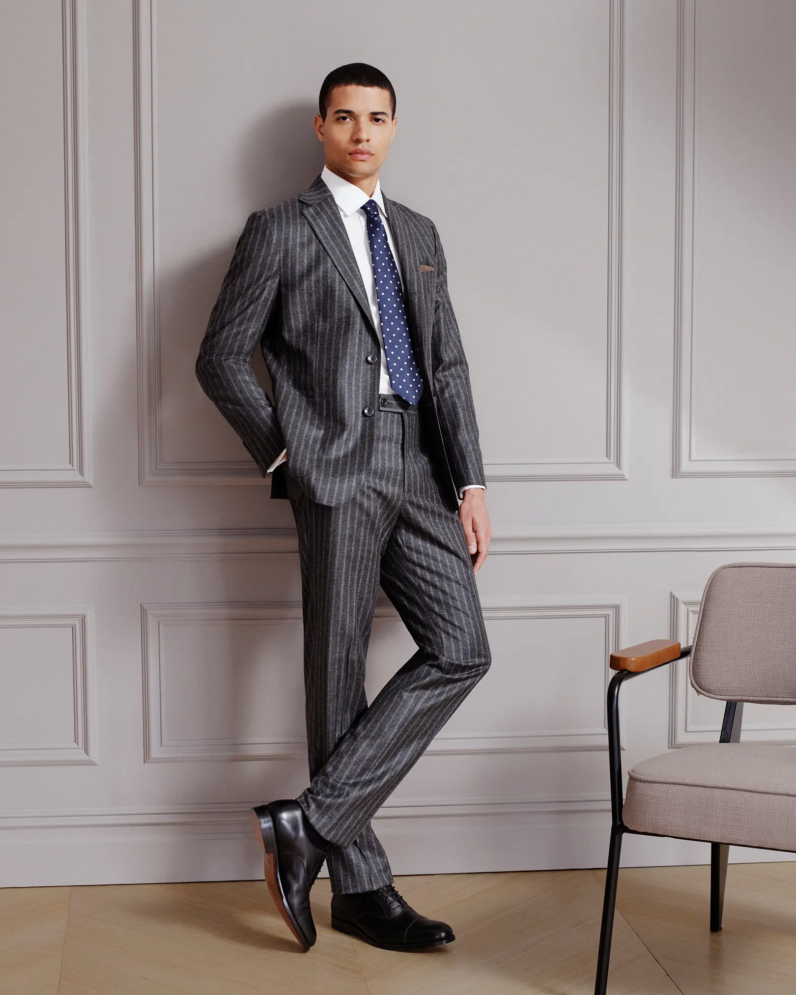 Man in a grey pinstripe suit and navy polka-dot tie