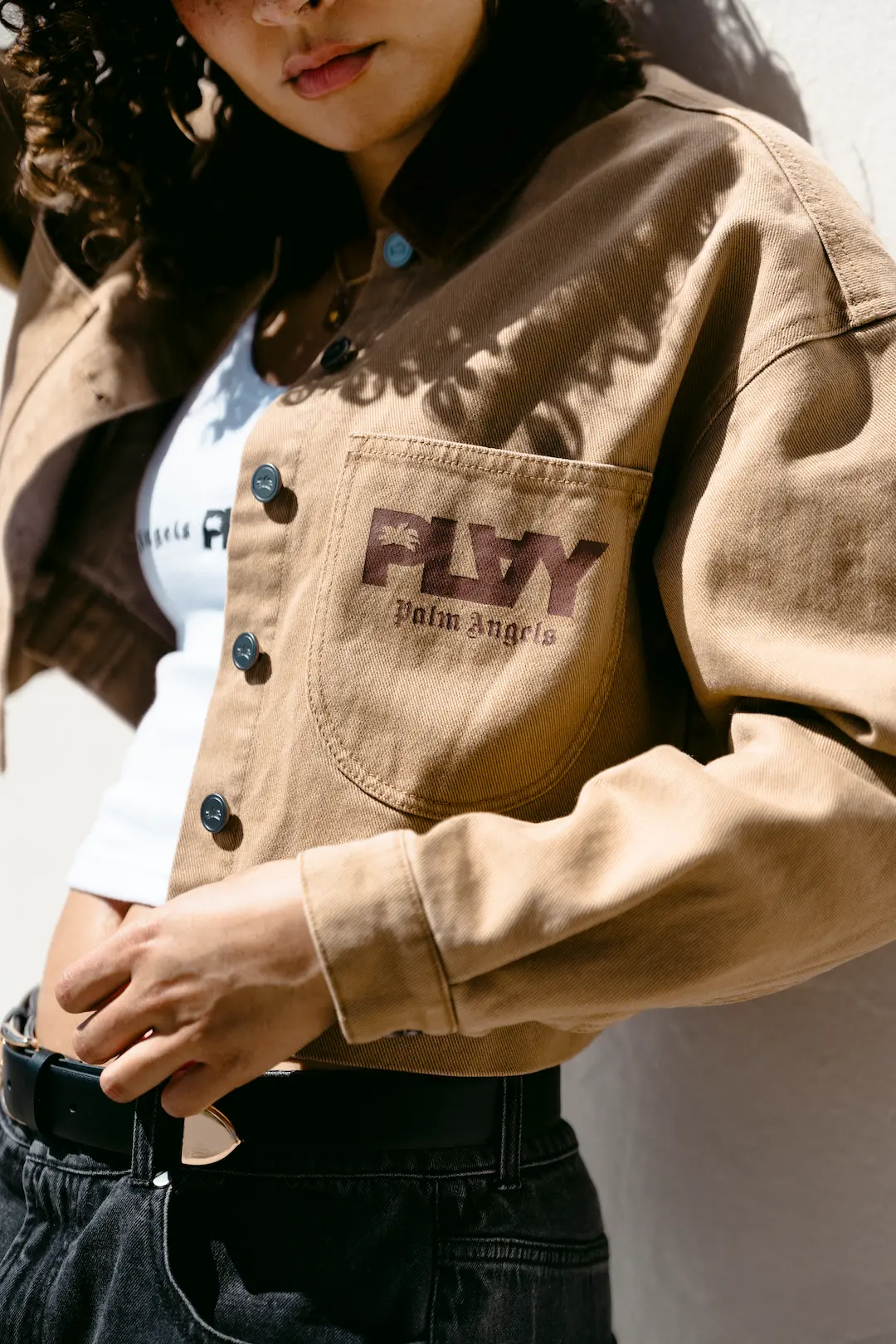Person in a tan PLAY Palm Angels jacket, face cropped